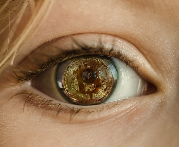 Close-up of an eye reflecting a Bitcoin coin