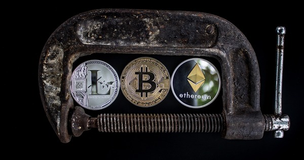 Litecoin, Bitcoin and Ethereum coins held together in a clamp