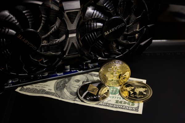 Bitcoin, Ethereum and Ripple coins with US dollar banknotes